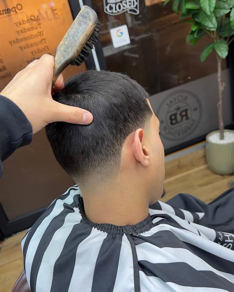 Barber brushing off a fresh taper fade